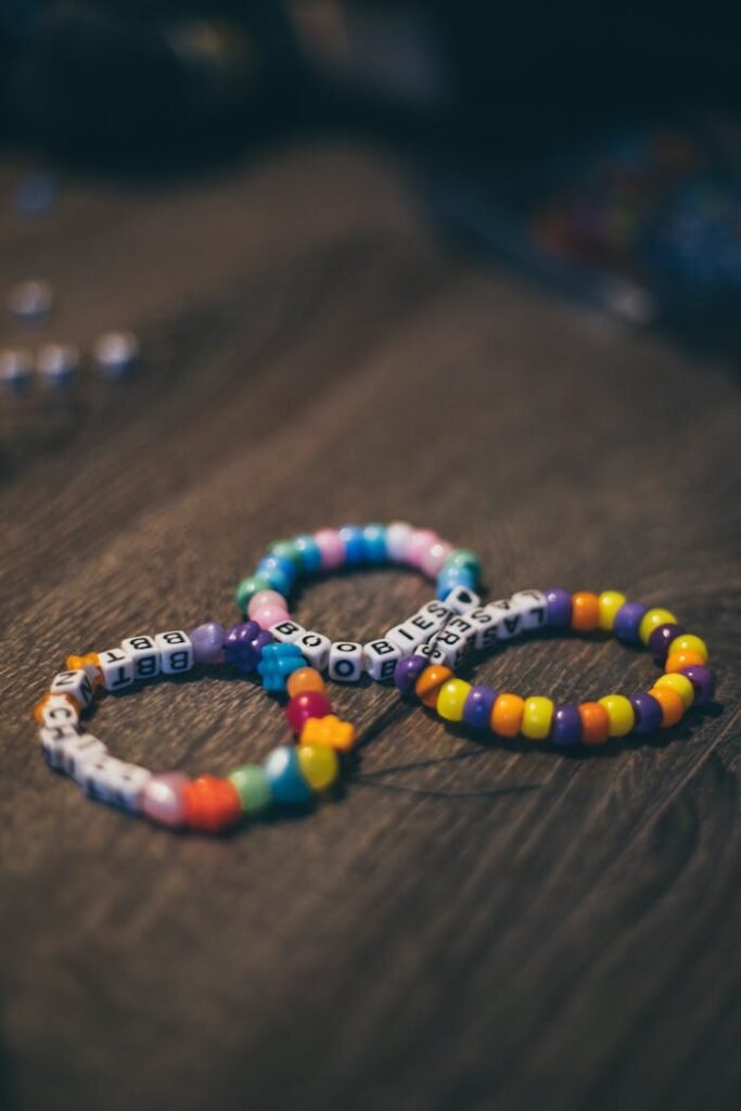 Vibrant bead bracelets featuring letters arranged on a rustic wooden background.